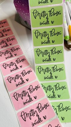 some pink and green stickers with writing on them next to marker pens, pencils and markers