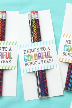 three colorful pencils sitting on top of each other in front of some greeting cards