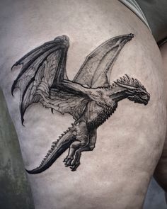 a black and white photo of a dragon tattoo on the side of a man's thigh