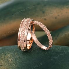 two gold wedding bands with intricate engraving on the sides, sitting on top of each other