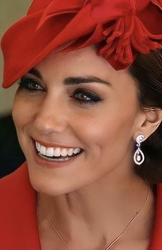 a woman wearing a red hat with flowers on it's head and smiling at the camera