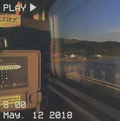 the train is traveling down the tracks next to the water and mountains in the distance