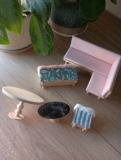 three miniature furniture sitting on top of a wooden floor next to a potted plant