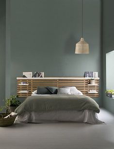 a bed sitting in a bedroom next to a wall mounted light above it's headboard