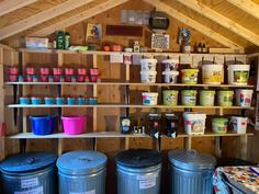 several buckets and containers are on shelves in a shed