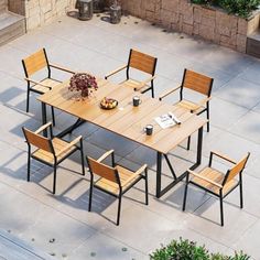 an outdoor dining table with six chairs and a potted plant on the side walk