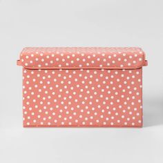 a pink and white polka dot pattern storage box with handles on the top, sitting against a gray background