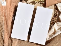 two white cards sitting on top of a table next to some dried grass and other items