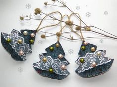 three ornaments are hanging from some twigs on a table with snowflakes in the background