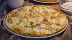 two pies sitting on top of a white plate next to a bowl of flour