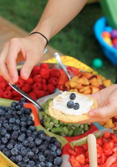 a person is cutting up some food on a plate with berries and blueberries in it