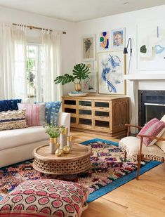 a living room filled with lots of furniture and paintings on the wall above it's fireplace