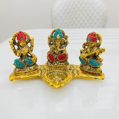 three golden ganeshi figurines sitting on top of a white table next to each other