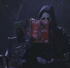 a person sitting on a bench with a book in their hand and a mask covering his face