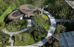 an aerial view of a circular house surrounded by trees and shrubs, in the middle of a park