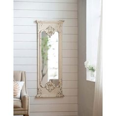 a white mirror sitting on the side of a wall next to a chair and window