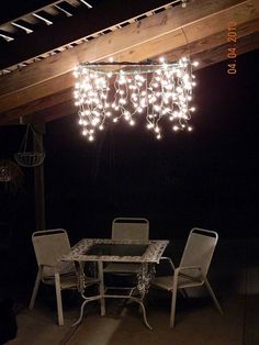 a table and chairs under a wooden roof with lights hanging from it's ceiling