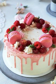 a cake decorated with raspberries and white frosting on top of a table