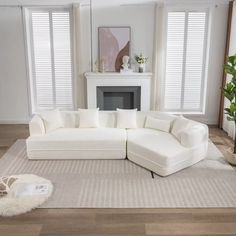 a large white sectional couch in a living room with windows and rugs on the floor