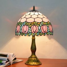 a lamp that is sitting on top of a table next to a book and pen