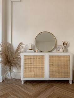 a white cabinet with wicker doors and a round mirror on it's side