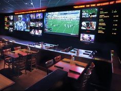 a sports themed restaurant with multiple televisions on the wall and tables in front of them