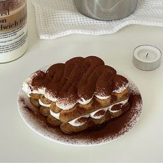 a white plate topped with chocolate covered waffles next to a jar of whipped cream