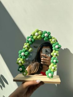 a woman taking a selfie with her cell phone in front of a green wreath