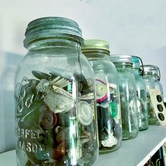 there are many jars that have various items in them on the shelf next to each other