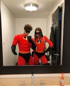 a man and woman dressed in costumes taking a selfie in front of a mirror