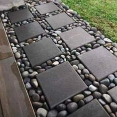 a walkway made out of rocks and stones with grass in the back ground behind it