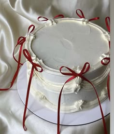 a white cake with red ribbon on top