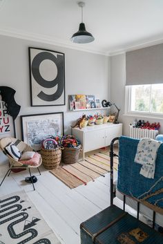 a child's bedroom with lots of toys on the floor and pictures on the wall