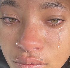 a close up of a woman's face with tears on her cheek and nose