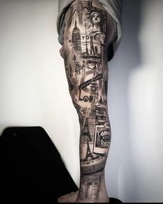 a man's leg with tattoos on it and some buildings in the back ground