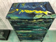 an artisticly painted chest of drawers in a room