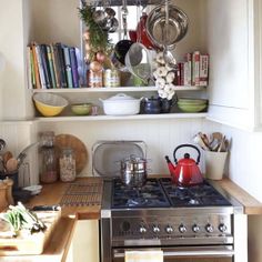 a stove top oven sitting inside of a kitchen next to a wooden counter topped with pots and pans