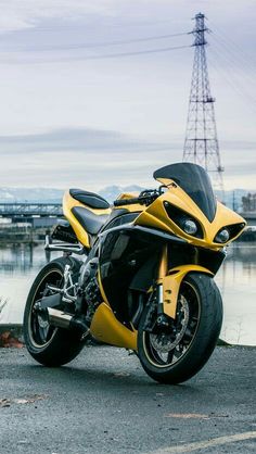 a yellow and black motorcycle parked next to a body of water