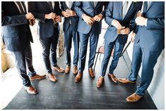 a group of men standing next to each other wearing suits and ties with their feet in the air