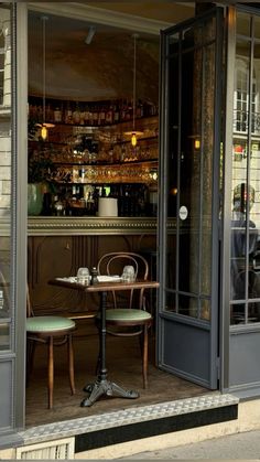 two tables and chairs in front of a bar with an open door to the outside