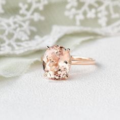 an oval shaped morganite sits on top of a white cloth