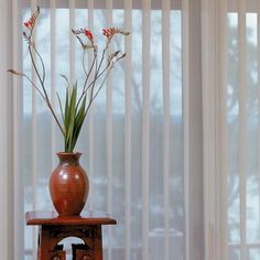 a vase filled with flowers sitting on top of a wooden table next to a window