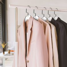 three suits hanging on a rail in front of a window and another suit hanger