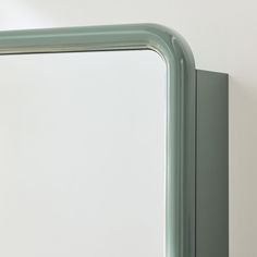 a green mirror mounted to the side of a wall