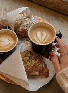 two cups of coffee and pastries on a plate