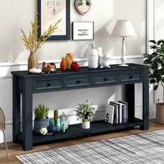 a black console table with three drawers and two vases on top, in front of a white wall