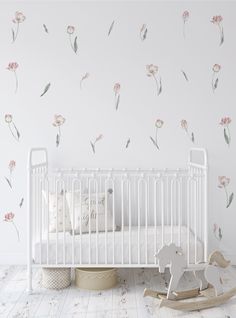 a white crib with pink flowers on the wall