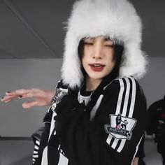 a person wearing a white furry hat and black hoodie with hands out to the side