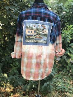 a plaid shirt with an image of a camper on the back and trees in the background