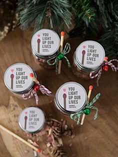 four small jars filled with candy canes on top of a wooden table next to a christmas tree